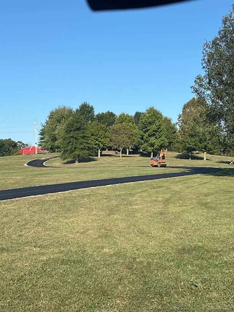 Recycled asphalt driveway winding across a Tennessee property past a red barn